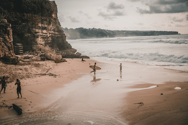 Surfers on a sandy beach in Bali embodying the vibrant local lifestyle for those considering the best visa to invest in Bali.